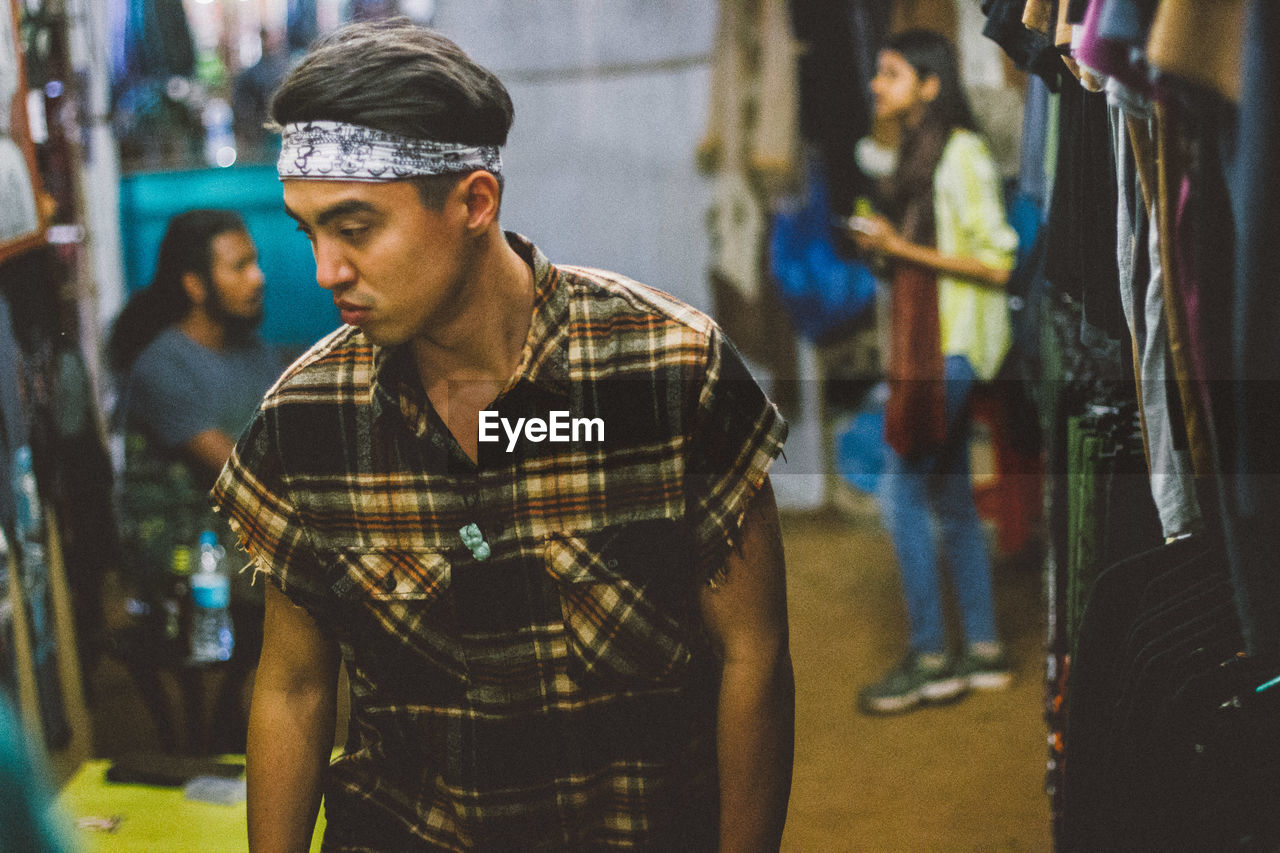 Side view of young man traveller standing in market 