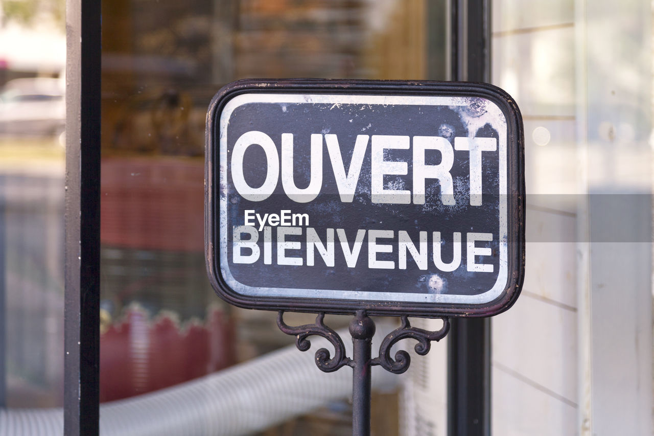 Outdoor open sign with written in it in french ouvert, bienvenue meaning in english open, welcome.