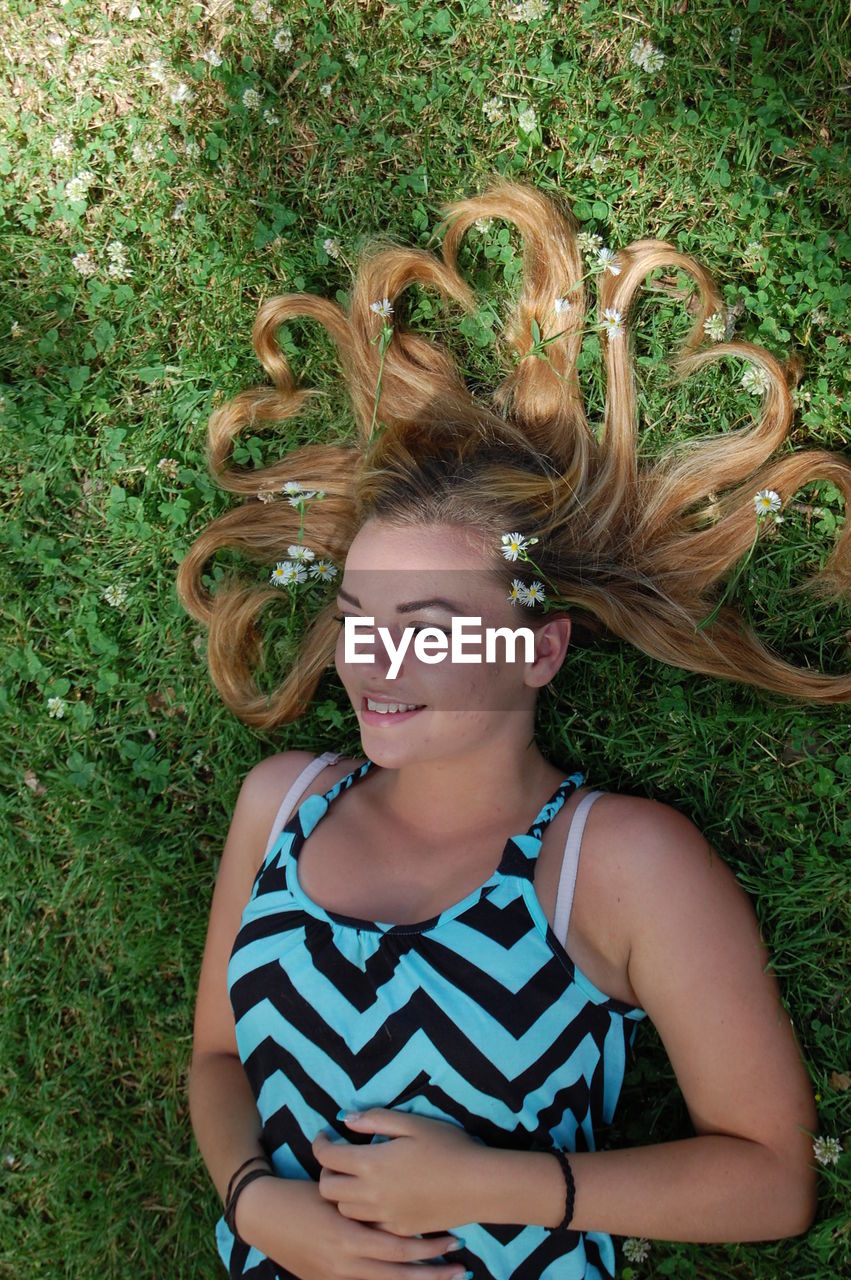 Directly above shot of happy woman hair with heart shape lying on field