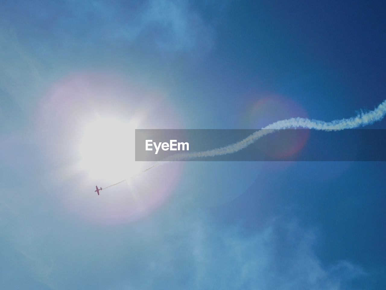 Low angle view of vapor trail against blue sky during sunny day