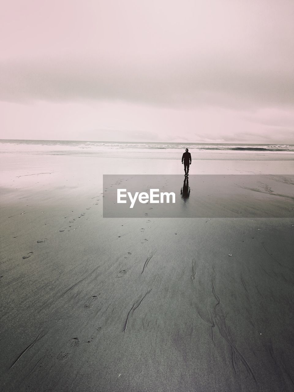 WOMAN STANDING ON BEACH AGAINST SKY