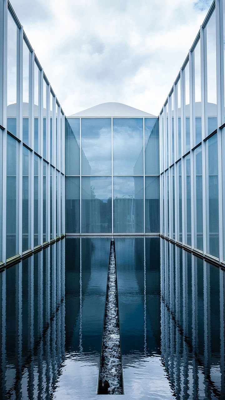 Pond with glass structure against sky