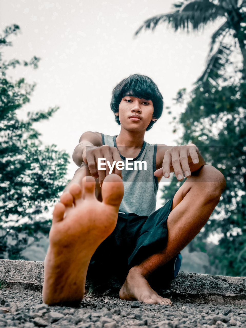 PORTRAIT OF A YOUNG MAN SITTING ON STONE