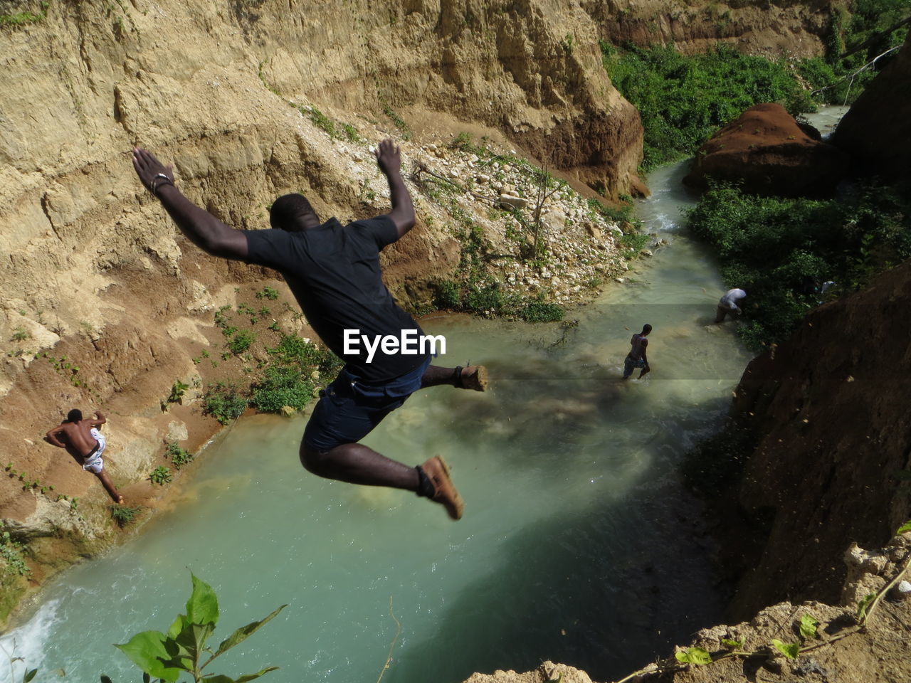 Man jumping off rock at shore