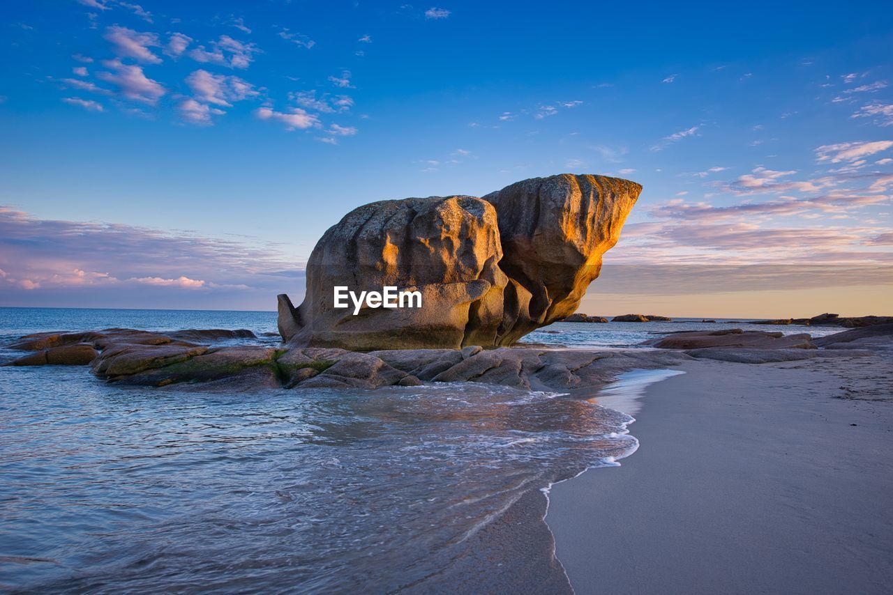 Rock formation on sea against sky during sunset