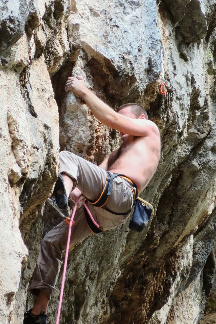 Low angle view of man with rope climbing on rock