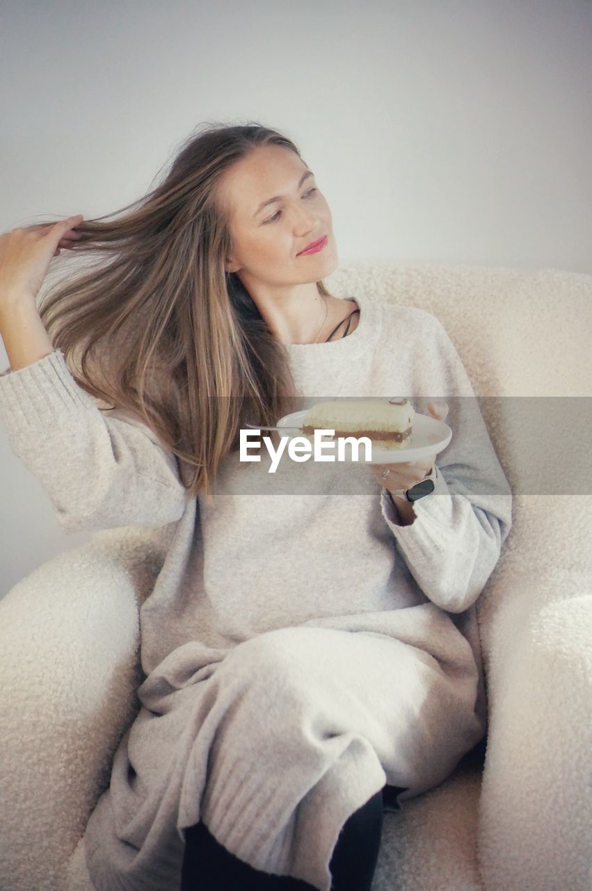 portrait of smiling young woman sitting on bed at home