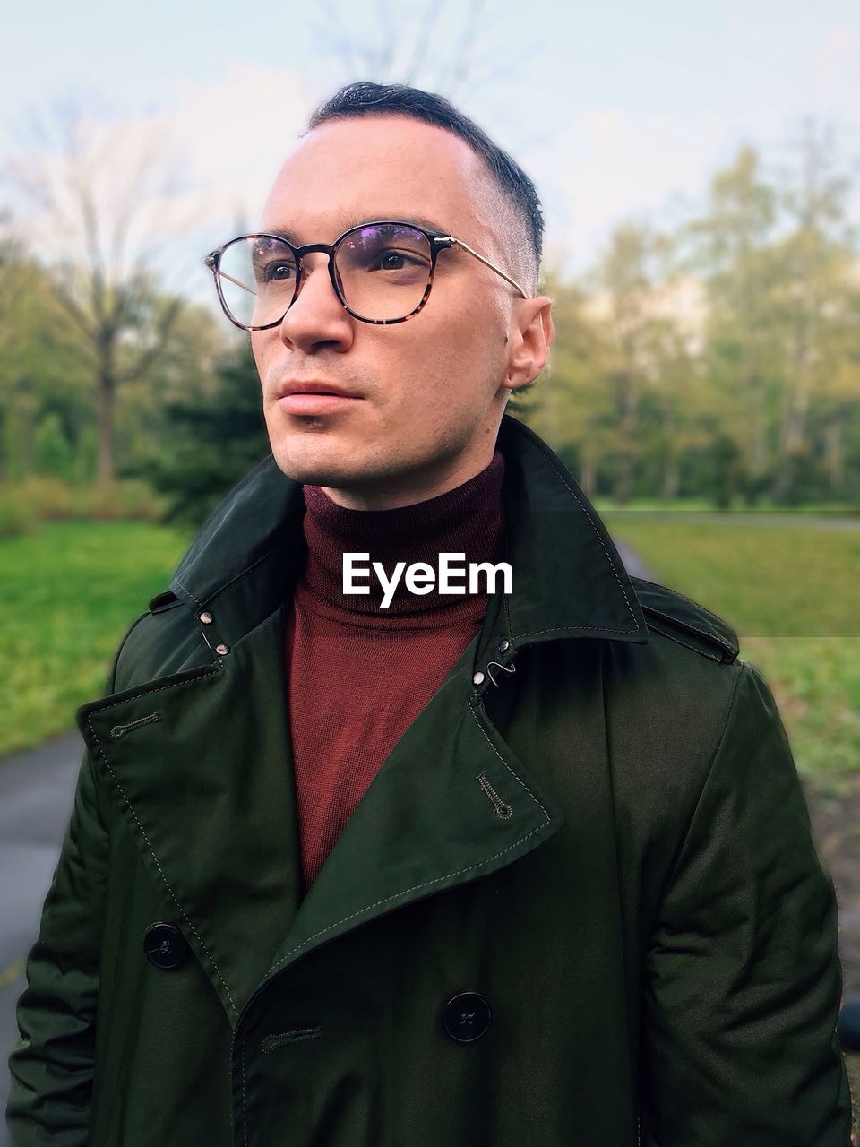 PORTRAIT OF YOUNG MAN WEARING EYEGLASSES STANDING AGAINST PLANTS