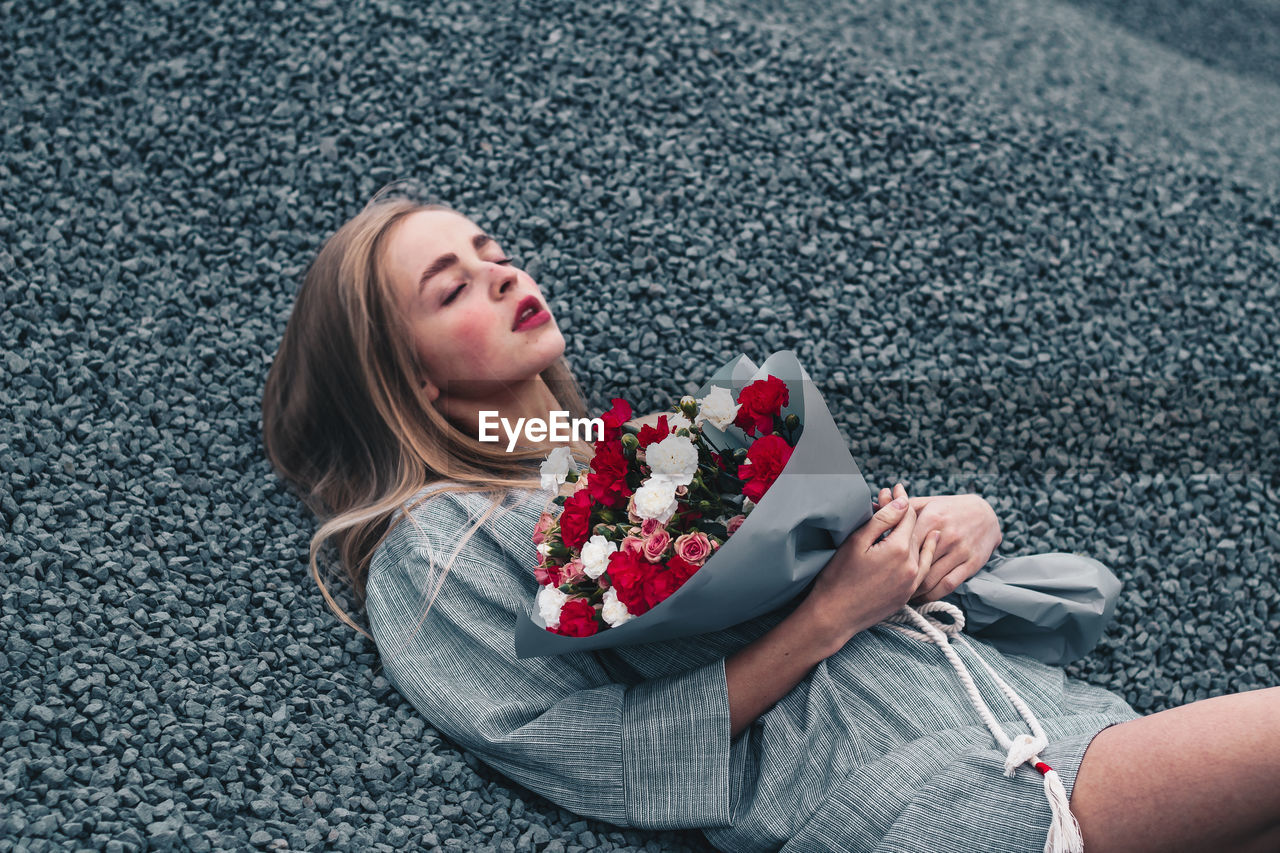 Close-up of woman holding bouquet lying on street