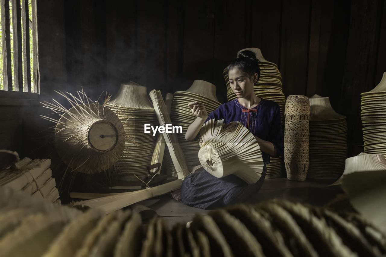 Woman weaving wicker hat in workshop