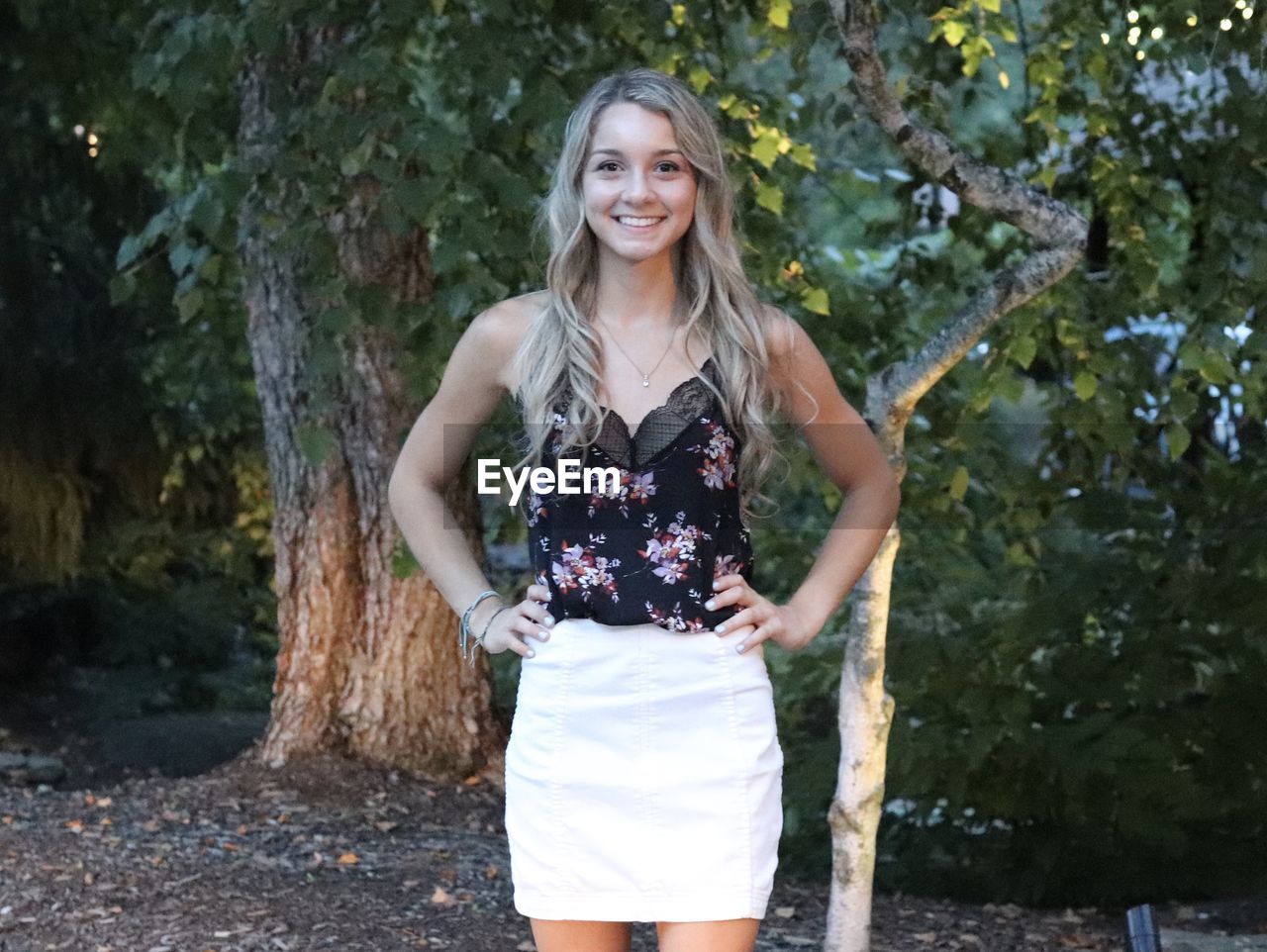 Portrait of smiling young woman standing against trees