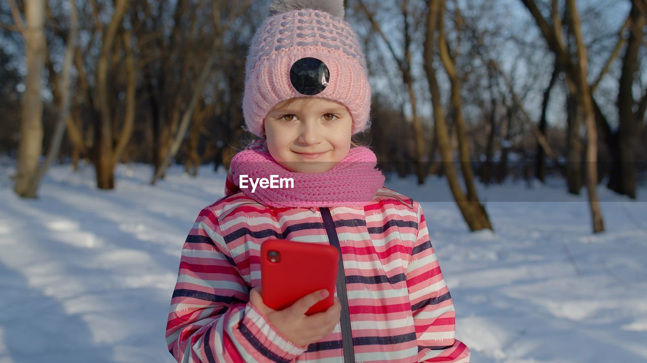 Portrait of girl holding mobile phone during winter