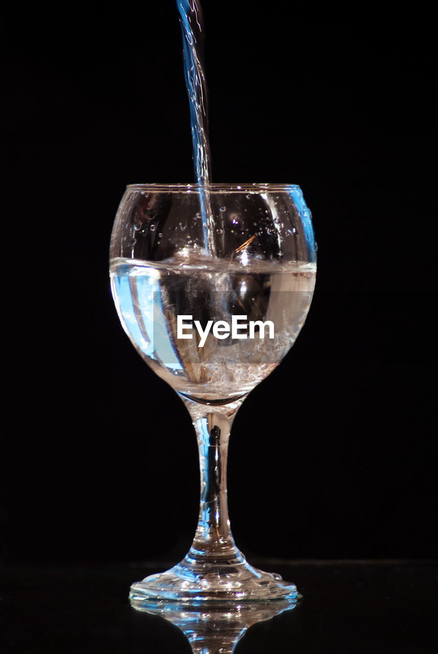 Close-up of wineglass on glass against black background