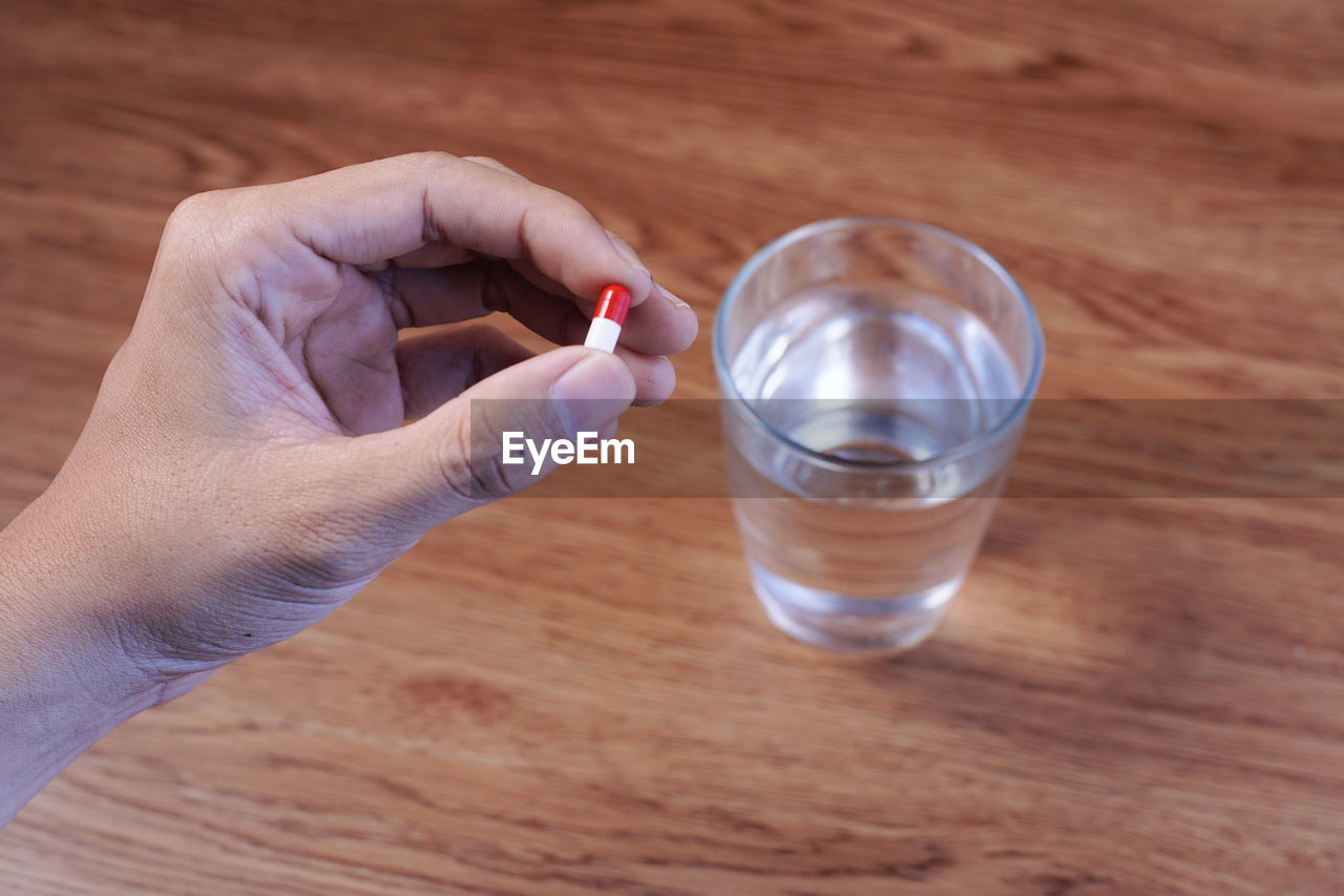 Cropped hand holding medicine over table