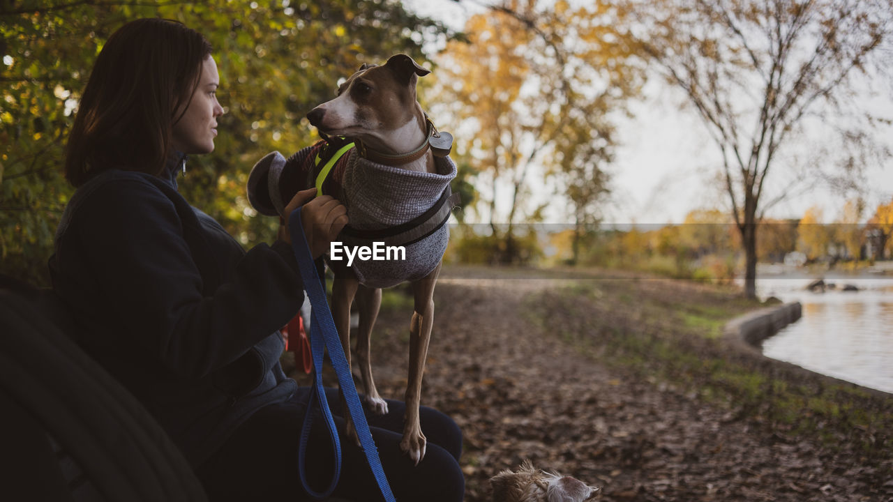 Woman sitting with dog on bench in park