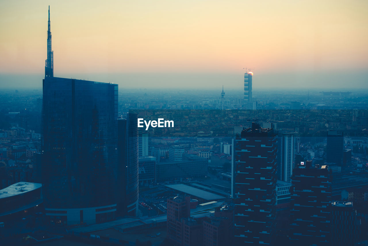 High angle view of modern buildings in city at sunset