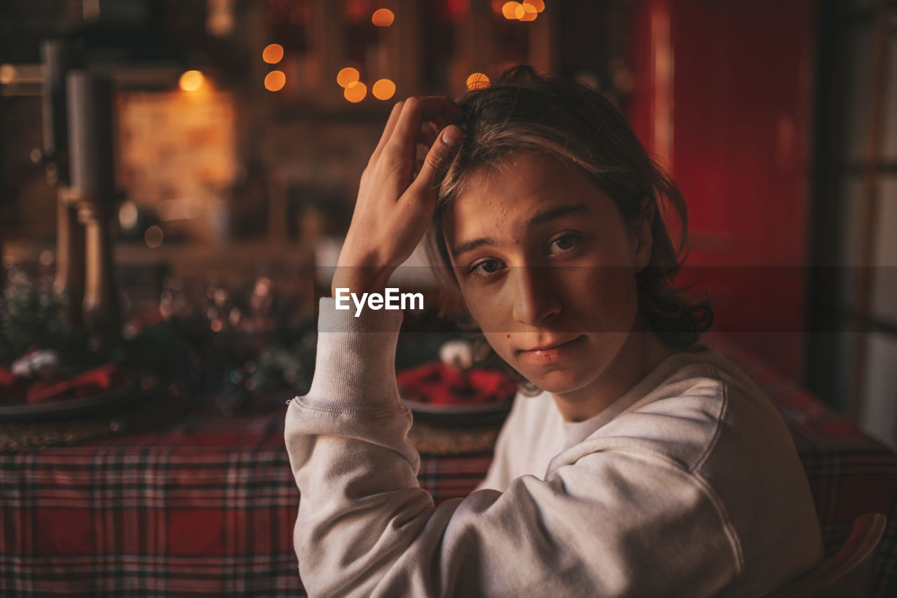 Portrait of candid authentic smiling handsome boy teenager using mobile phone at xmas home interior