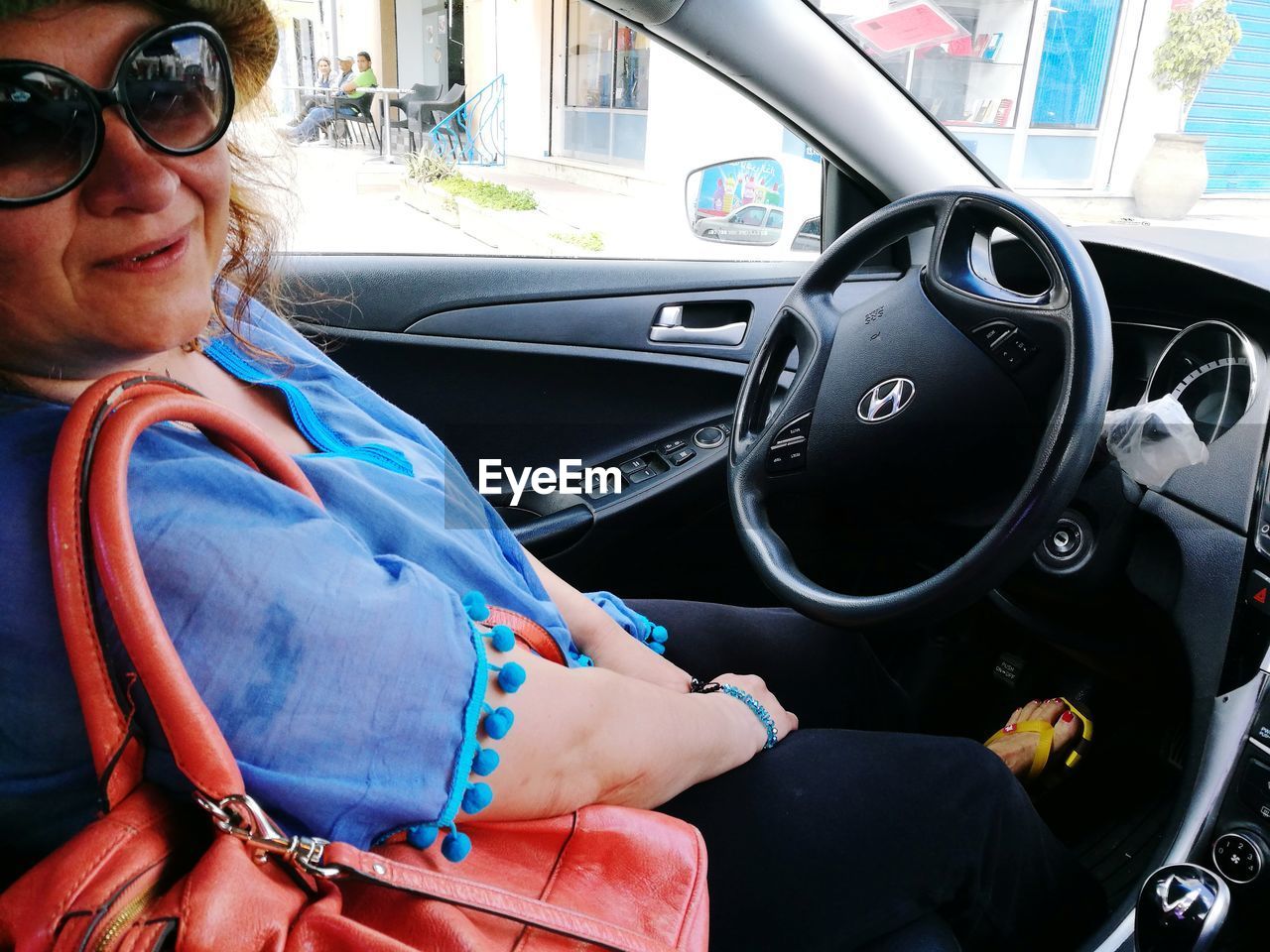 REFLECTION OF MAN IN SUNGLASSES SITTING ON CAR