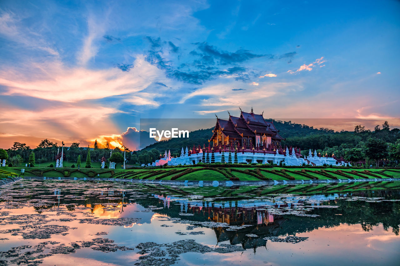 REFLECTION OF BUILDING IN LAKE AT SUNSET