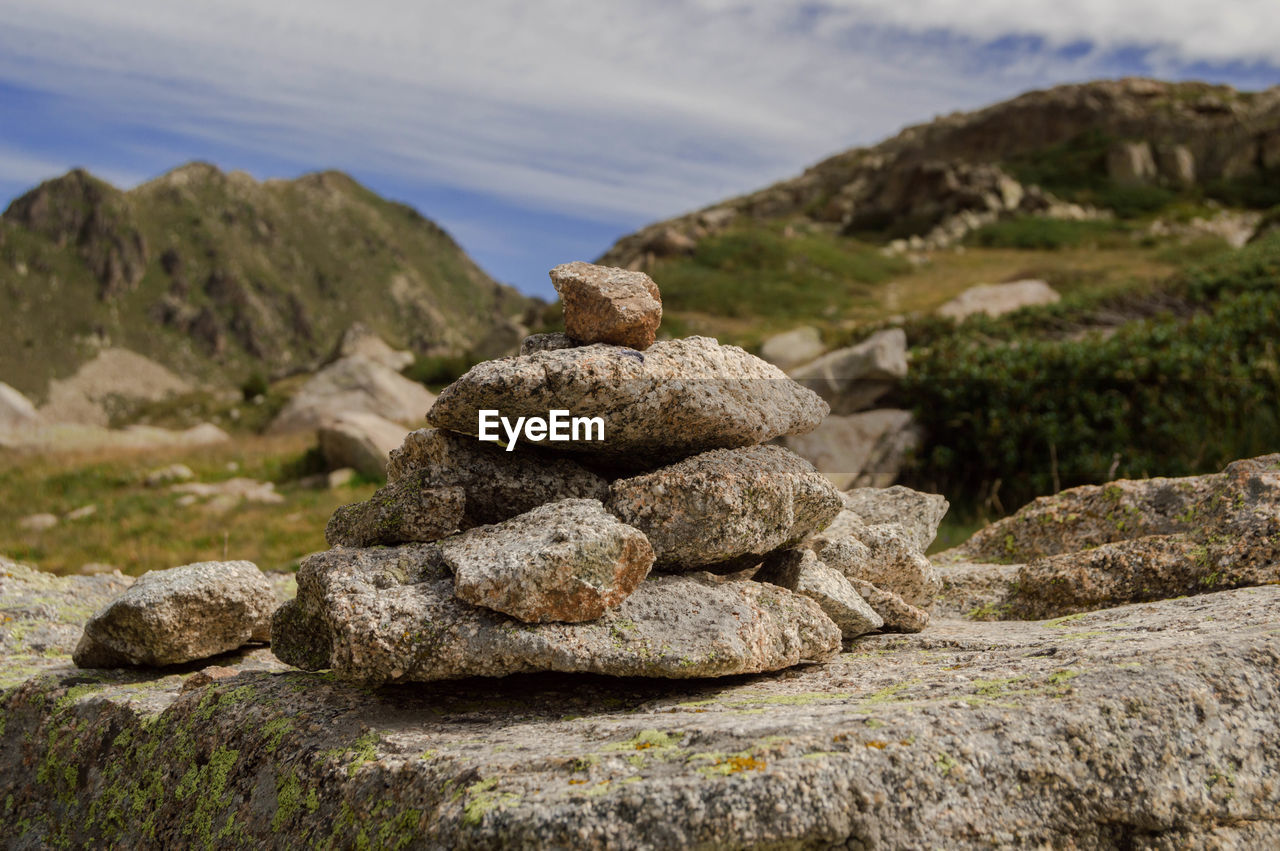 Stack of stones on rock against sky