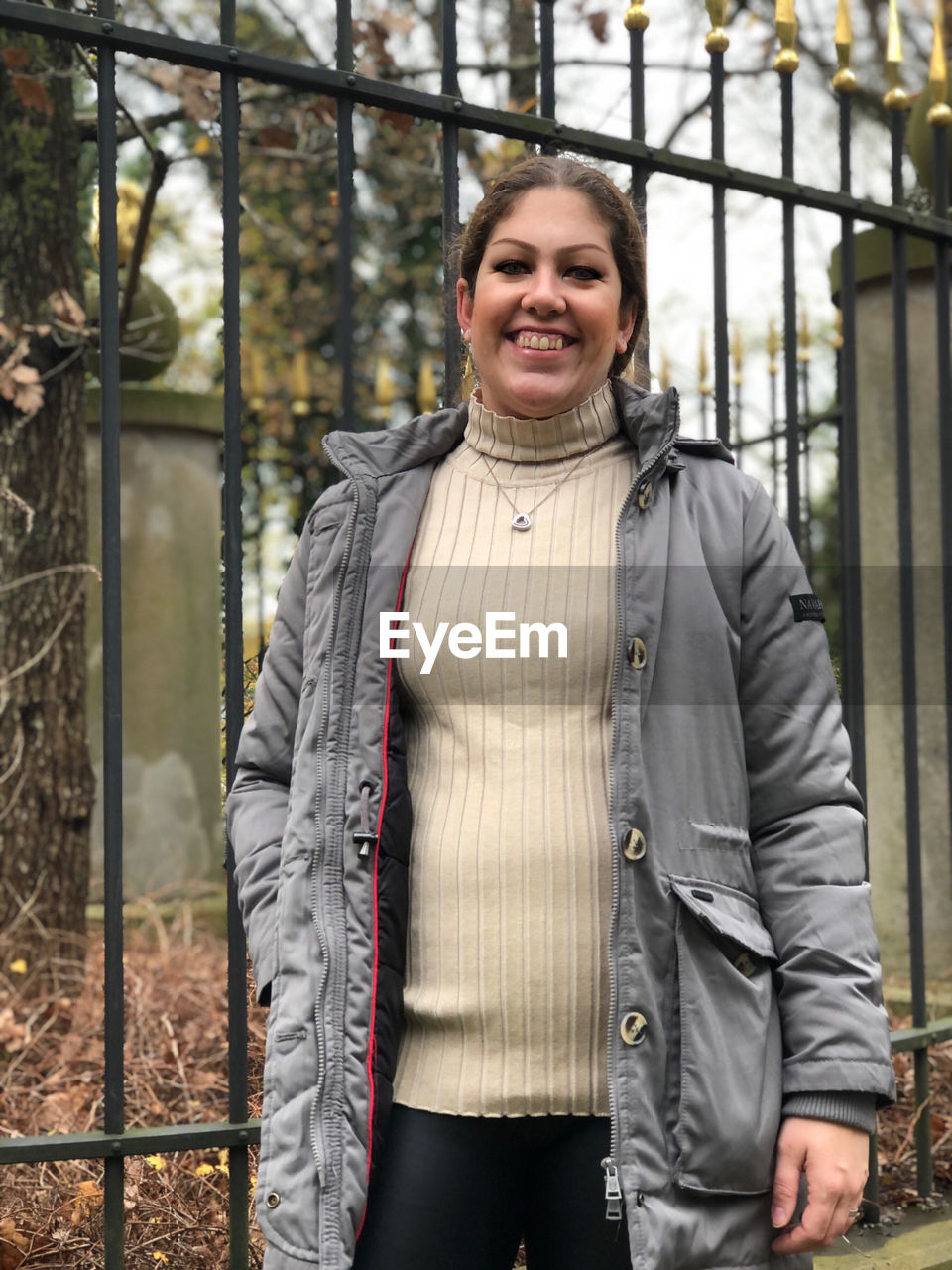 PORTRAIT OF SMILING WOMAN STANDING OUTDOORS