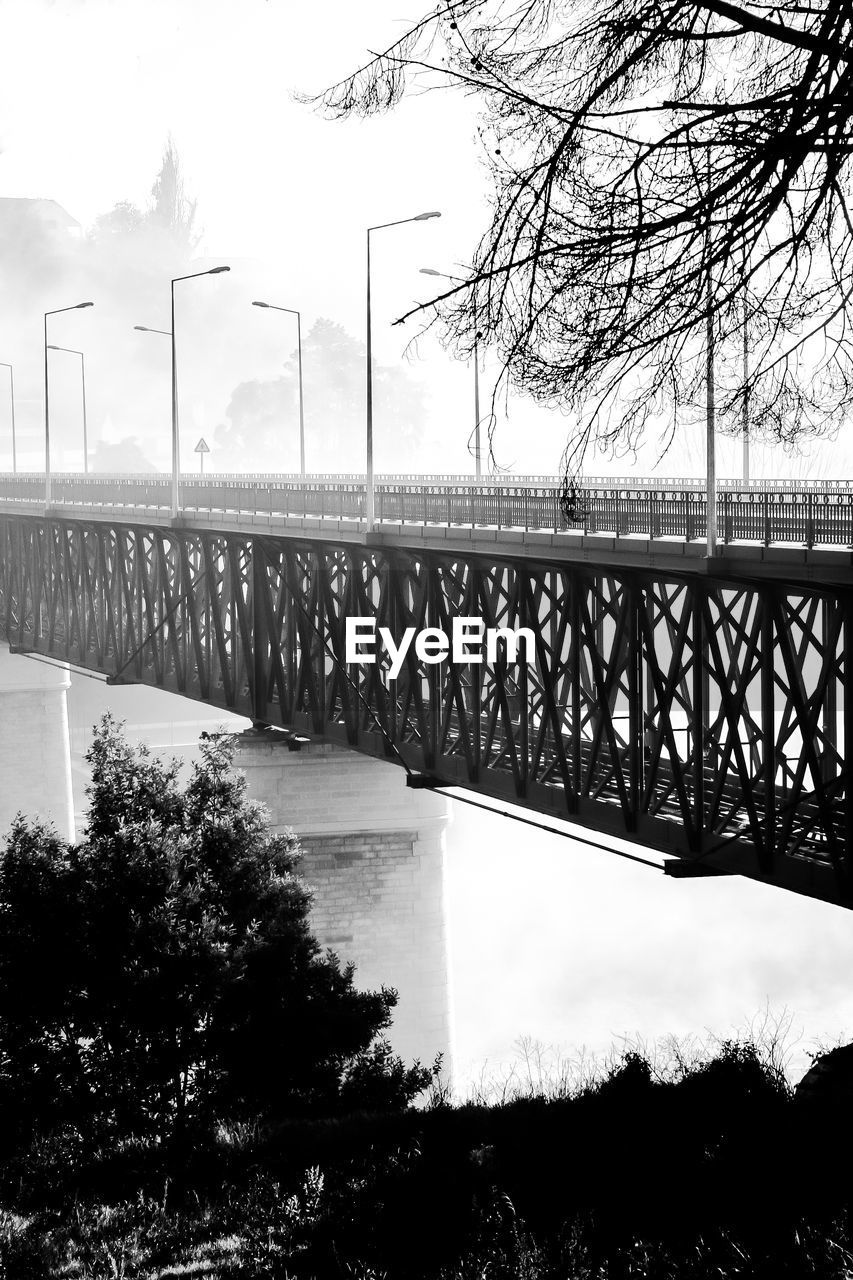 BRIDGE OVER RIVER BY BARE TREES AGAINST SKY