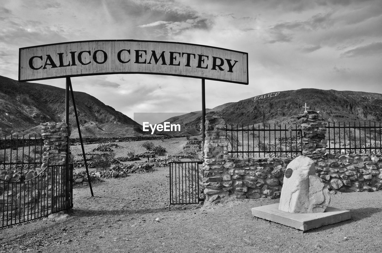 Cemetery sign on landscape against cloudy sky in ghost town in america