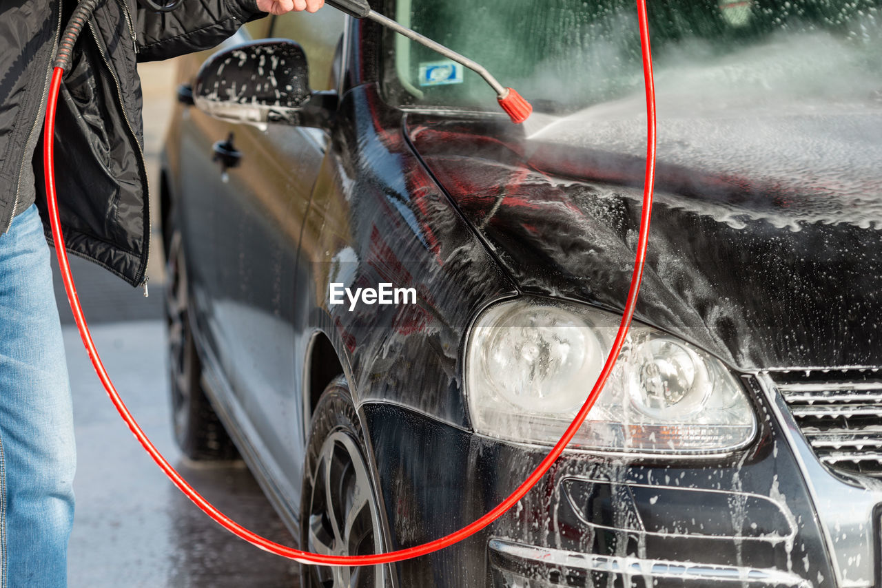 Man spraying water on car