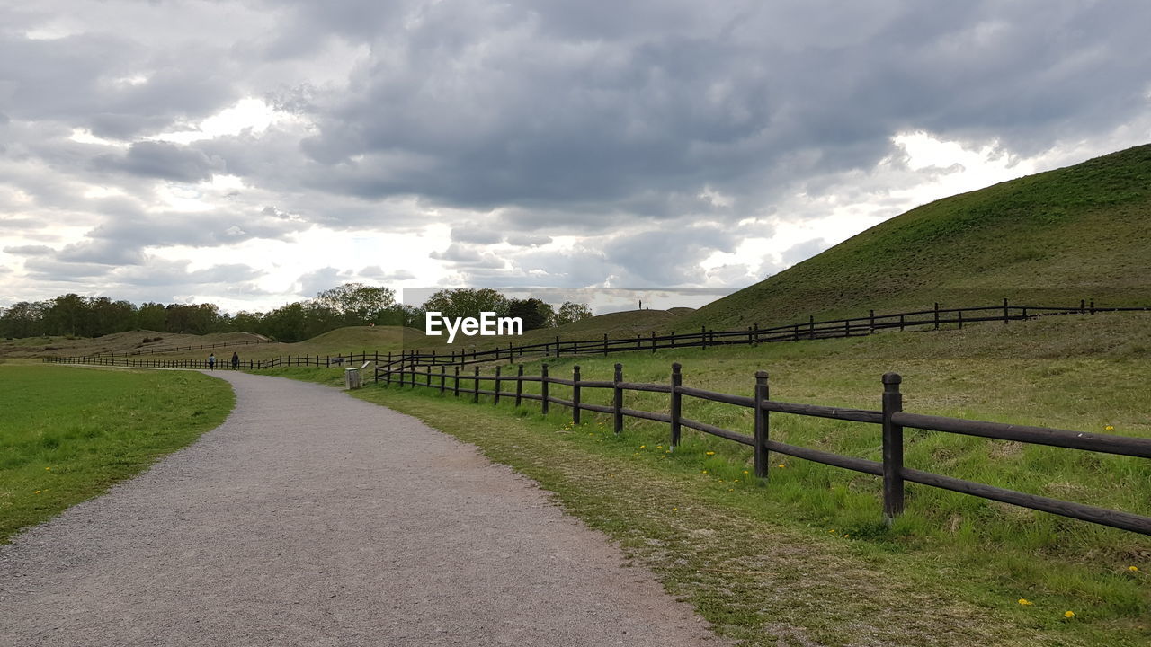 Road amidst field against sky