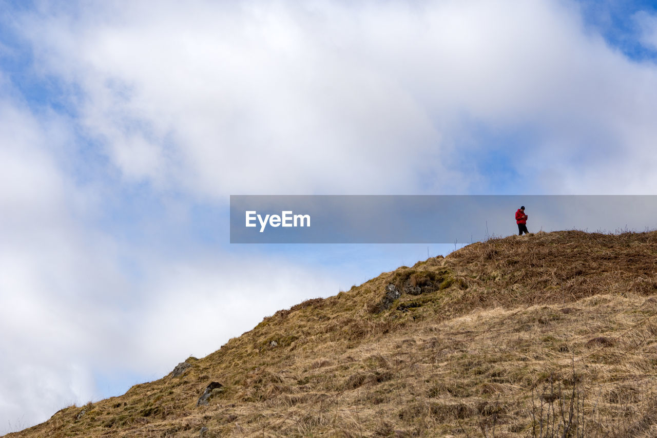 Low angle view of man standing on cliff against sky