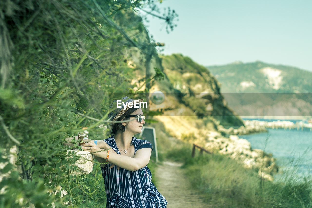 Woman standing by tree against mountain