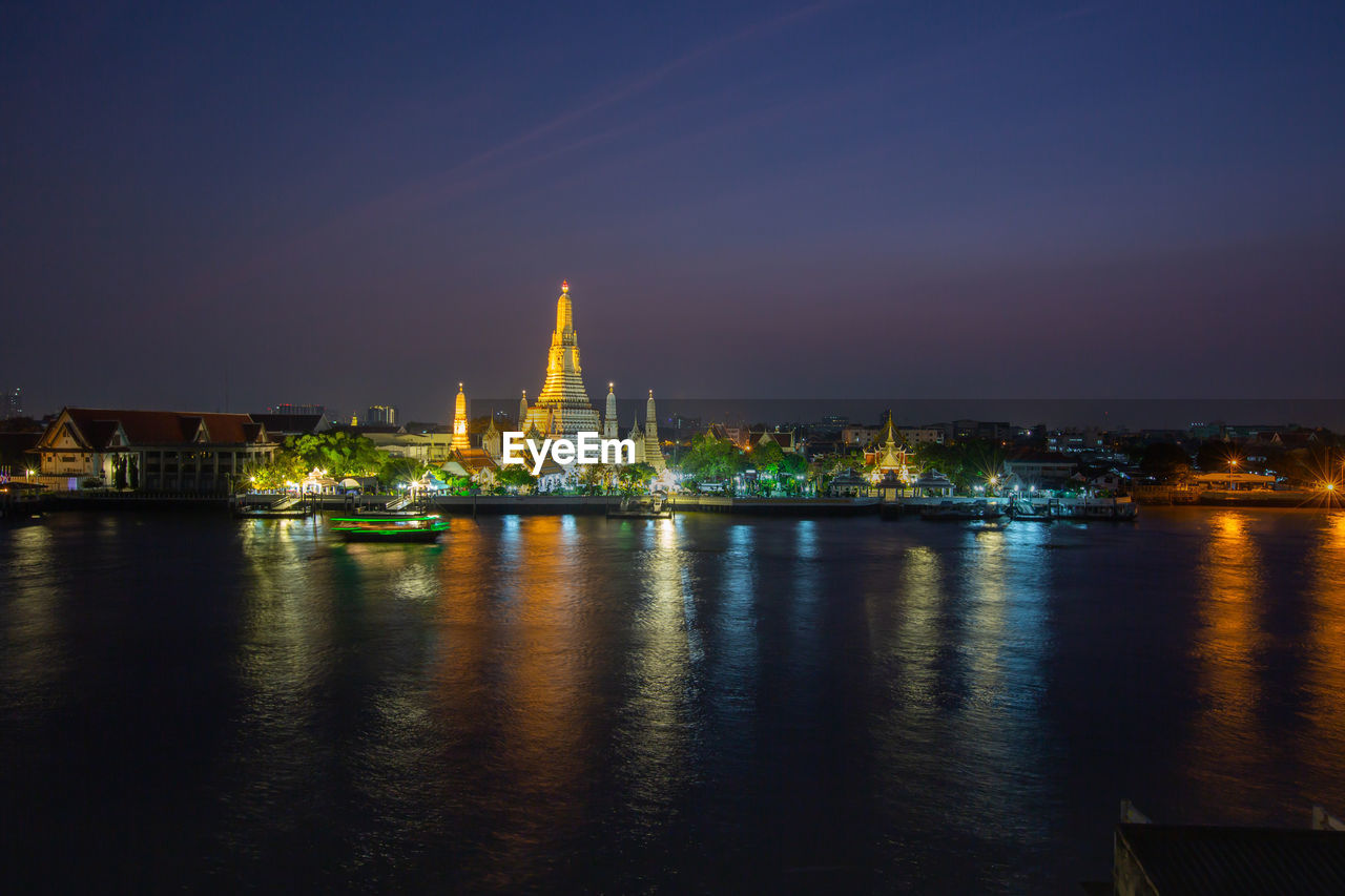 VIEW OF ILLUMINATED BUILDINGS AT WATERFRONT