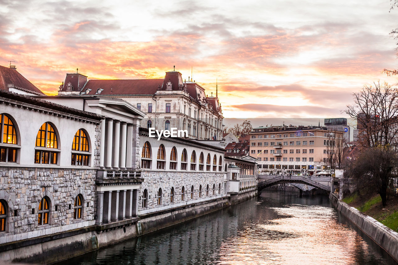 BRIDGE OVER RIVER BY BUILDINGS AGAINST SKY