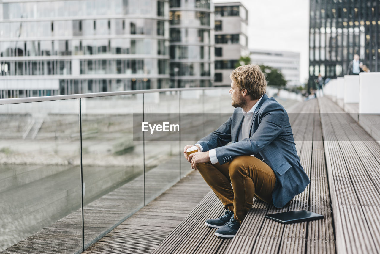 Businessman sitting on bridge having coffee break