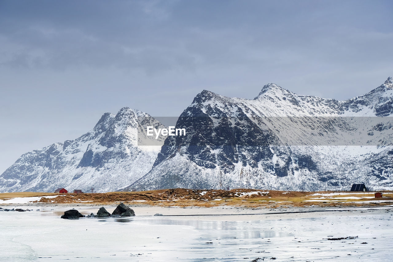 Scenic view of sea by snowcapped mountain against sky