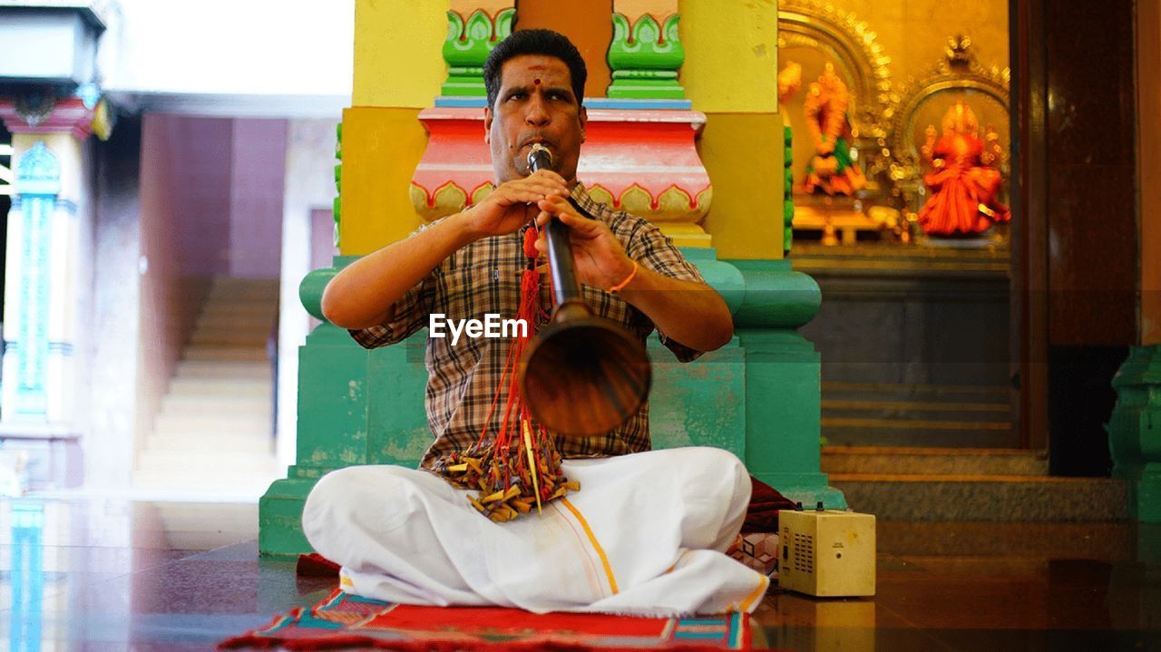 Close-up of a mature man playing a flute in a fort, meherangarh fort