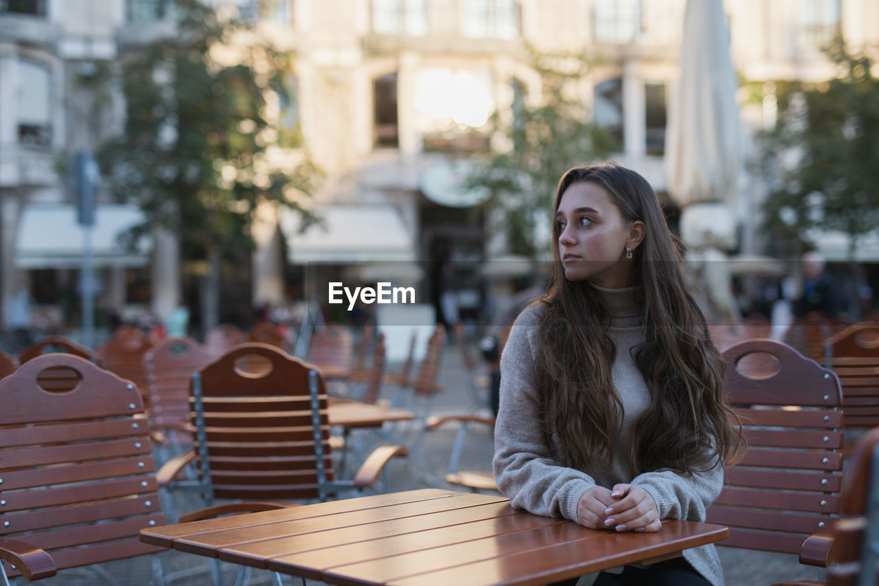 Young woman sitting on table in city