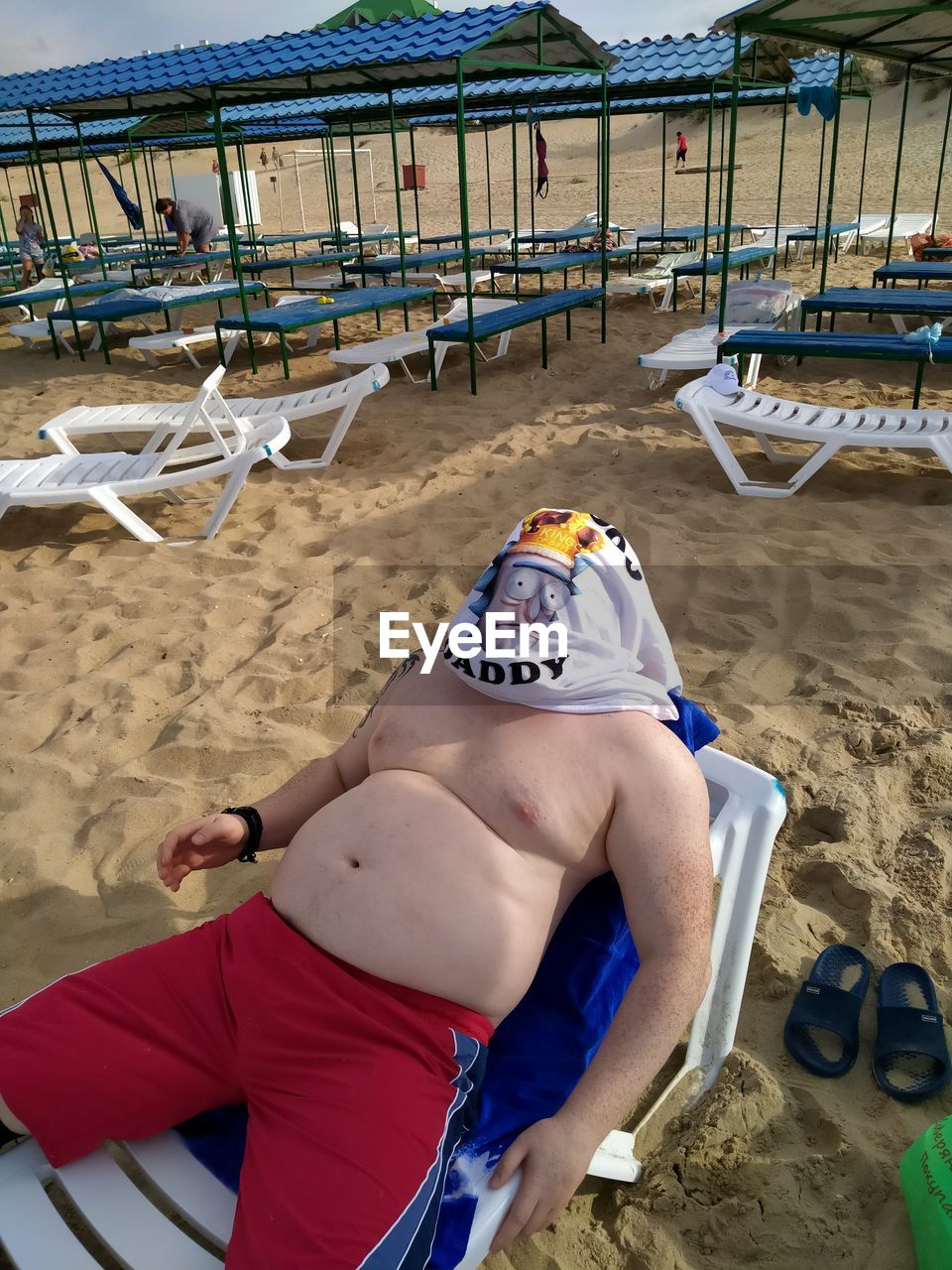 FULL LENGTH OF SHIRTLESS MAN LYING DOWN ON BEACH