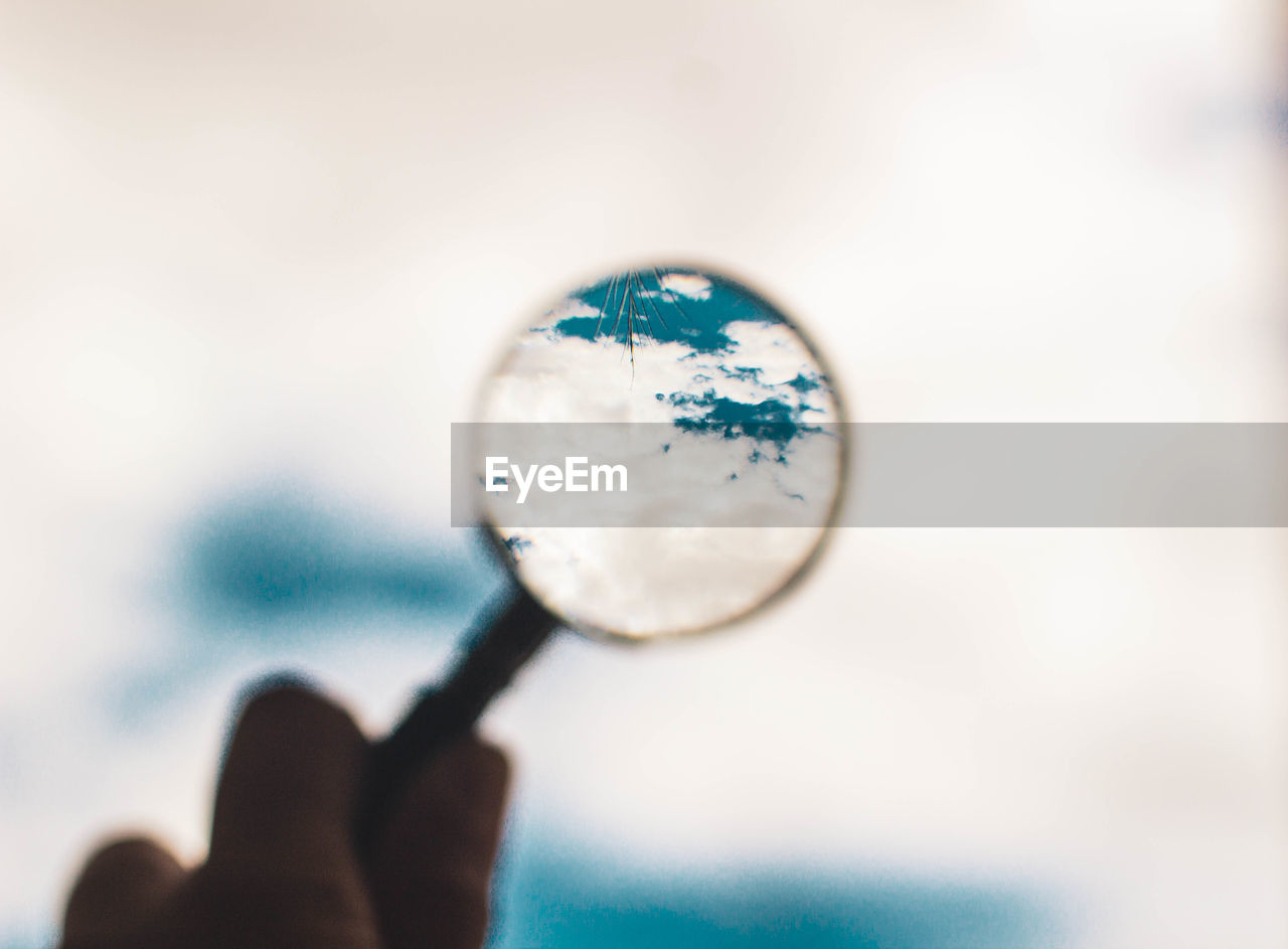 Magnifying glass pointing at cloudy blue sky