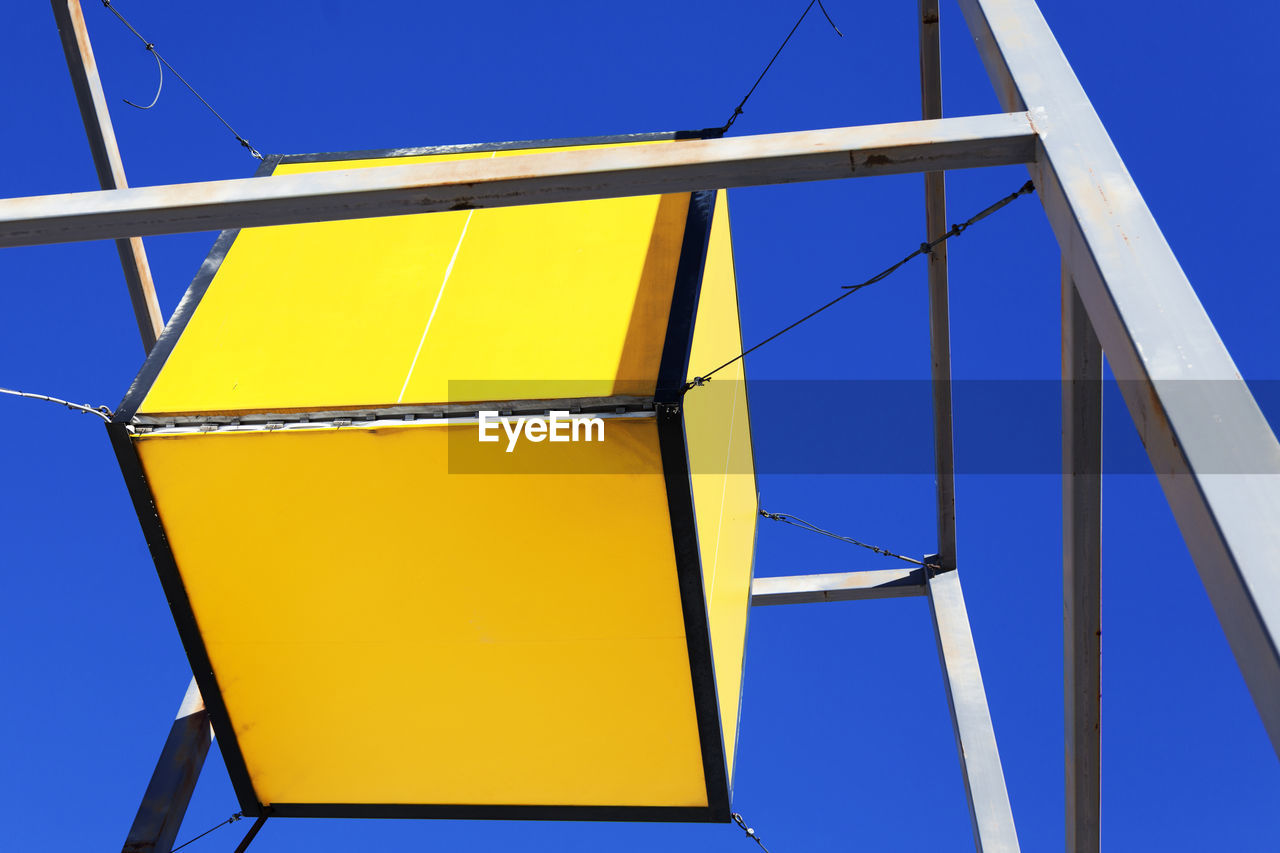 Large yellow cube hanging outside a hardware store