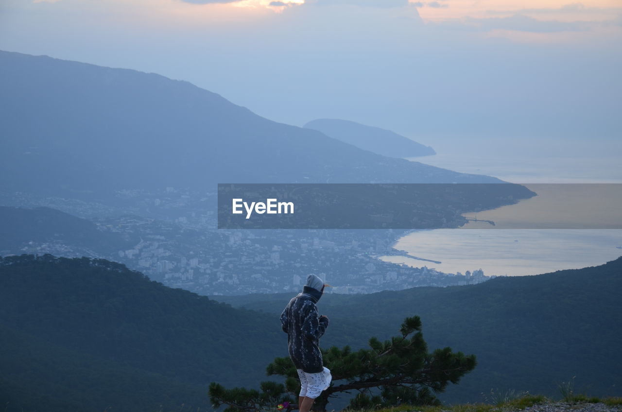 Rear view of people looking at mountains against sky