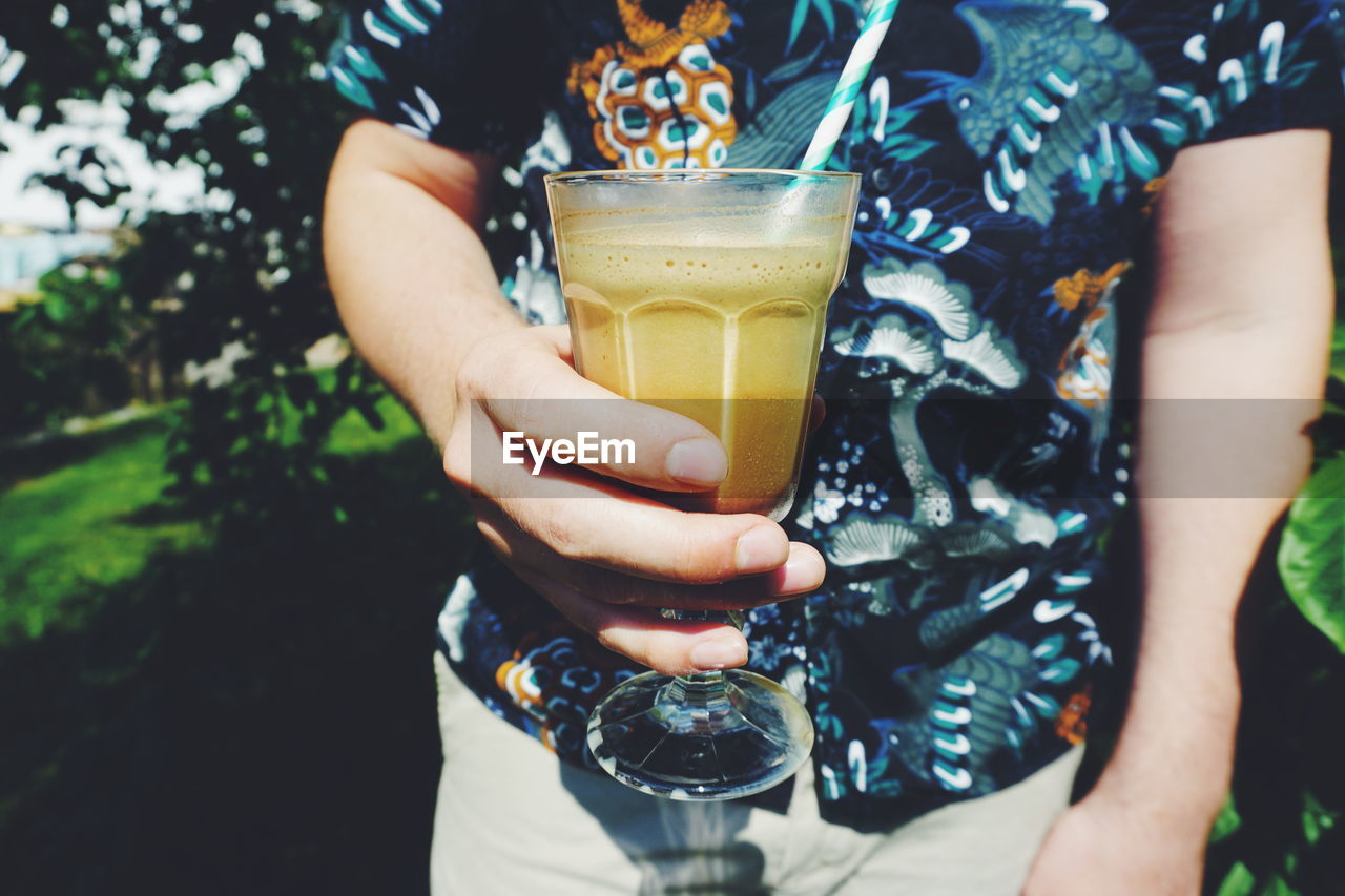 Midsection of man holding drink in glass