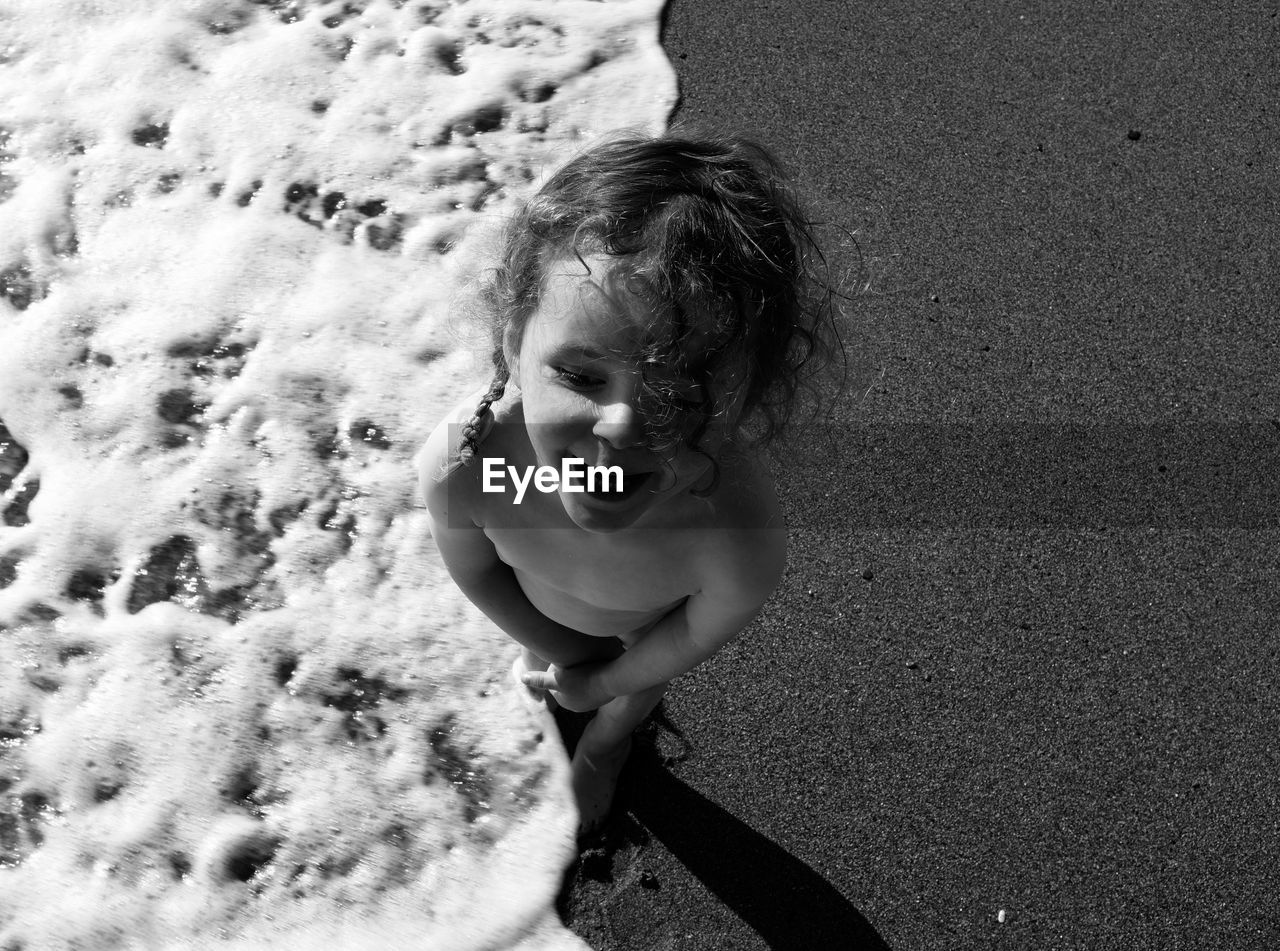 High angle view of shirtless girl standing on beach