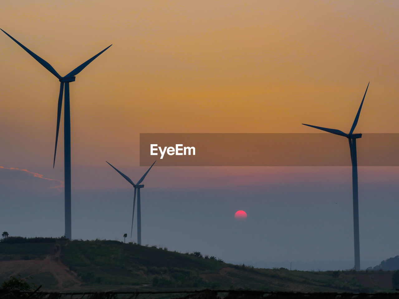 WINDMILL ON FIELD AGAINST SKY DURING SUNSET