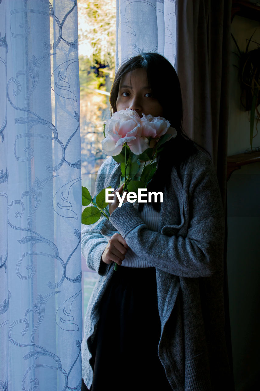 PORTRAIT OF WOMAN HOLDING PLANT