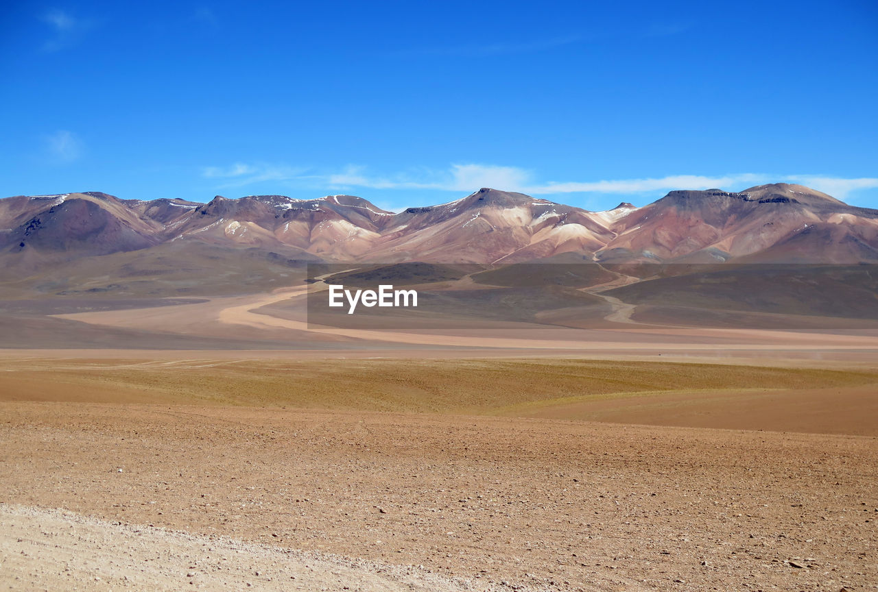 Scenic view of landscape and mountains against blue sky