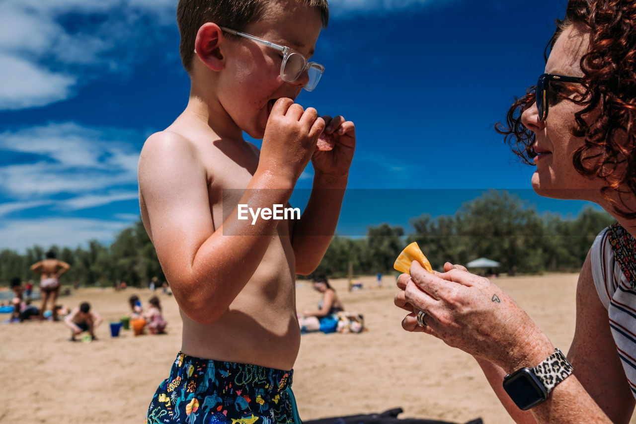 Close up of mother giving son a snack on the beach