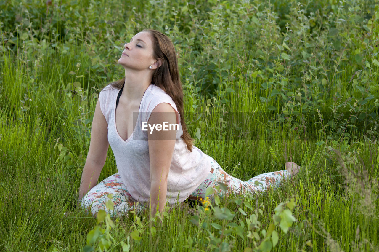 Young woman practicing yoga on grassy field