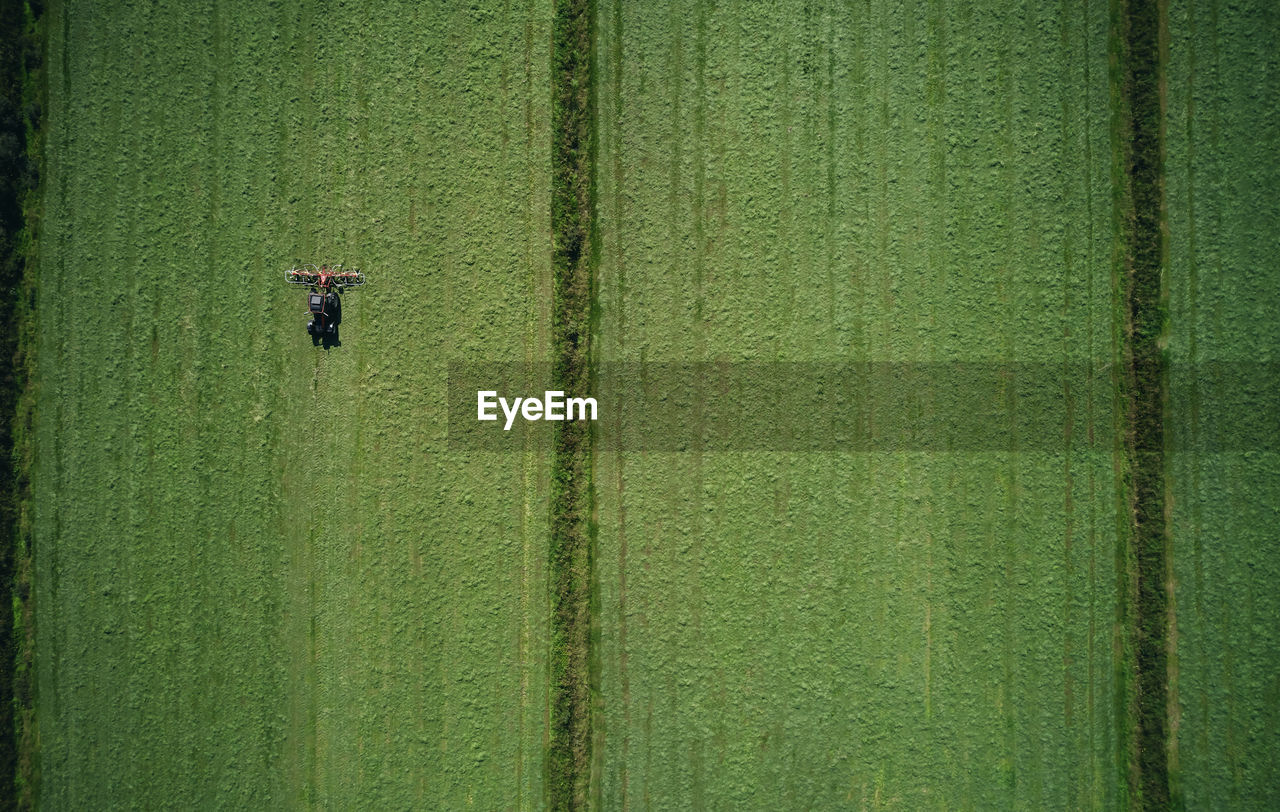 Powerful tractor evenly working on green field furrowing wheat