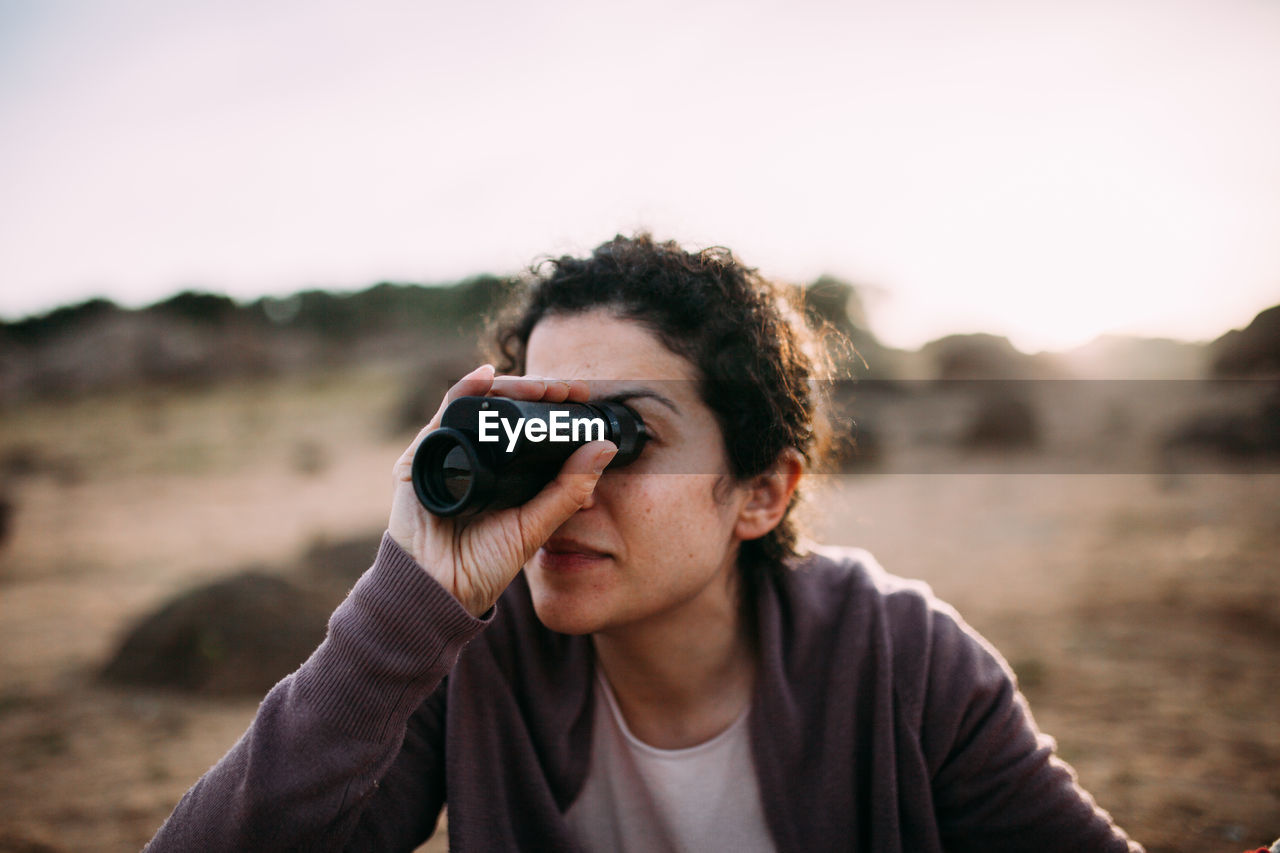Woman looking through binocular on field